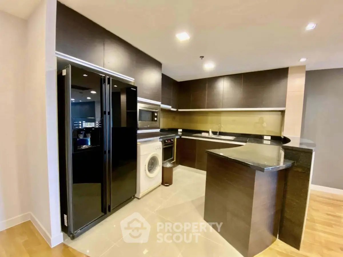 Modern kitchen with sleek black appliances and stylish cabinetry in a contemporary apartment.