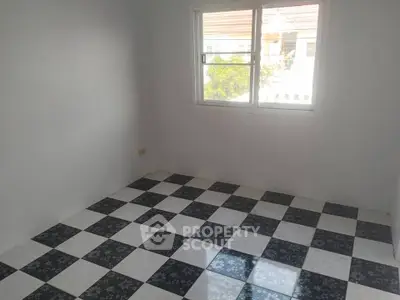 Spacious room with checkered tile flooring and large window offering natural light.