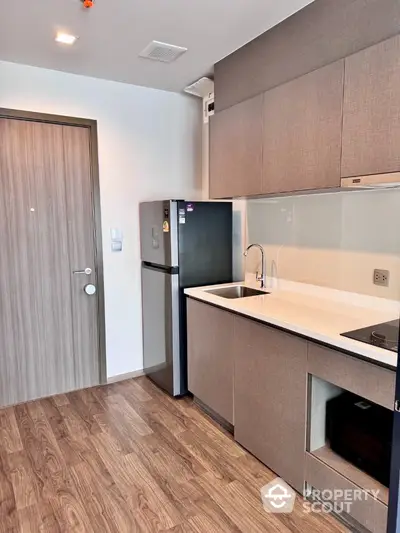 Modern kitchen with sleek cabinetry and wood flooring in a stylish apartment