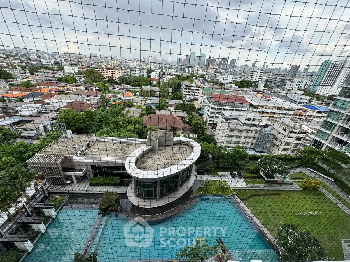 Stunning cityscape view from high-rise apartment overlooking pool and lush greenery.
