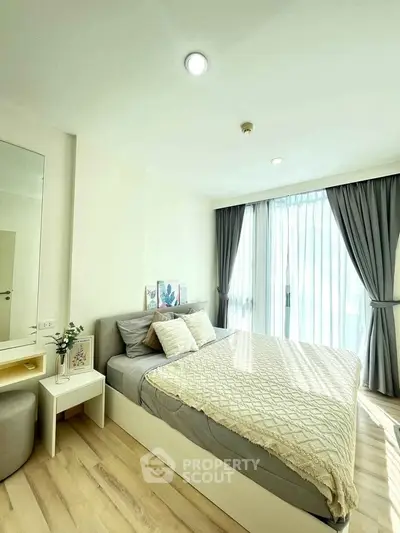 Bright and cozy bedroom with modern decor and large window for natural light.