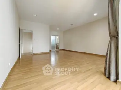 Spacious empty room with wooden flooring and natural light