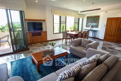 Spacious living room with modern decor and large windows opening to a balcony, perfect for relaxation.