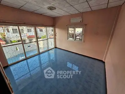 Spacious living room with large windows and blue tiled floor, offering ample natural light.