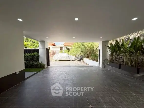 Spacious covered parking area with modern lighting and garden view.