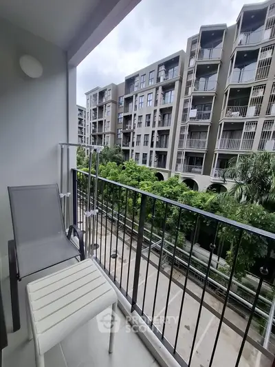 Modern apartment balcony with scenic view of lush greenery and contemporary building architecture.
