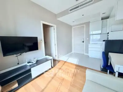 Bright modern living room with TV, sleek furniture, and ample natural light.