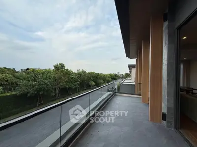 Spacious balcony with glass railing offering serene green views