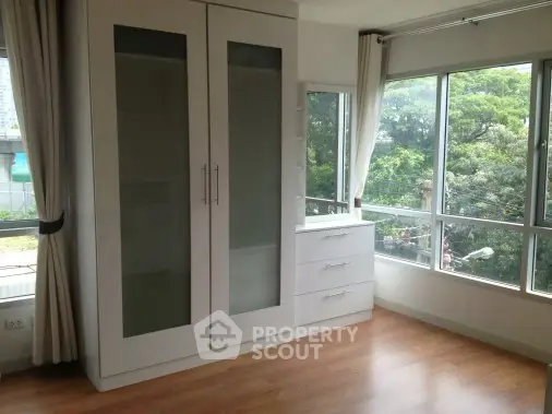 Spacious bedroom with large windows and built-in wardrobe overlooking greenery.