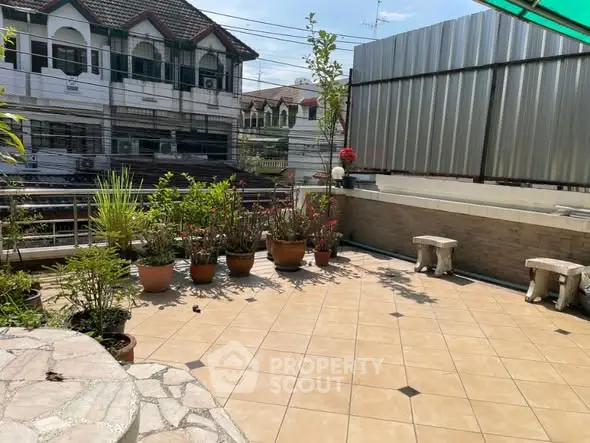 Spacious tiled balcony with potted plants and seating, ideal for outdoor relaxation.