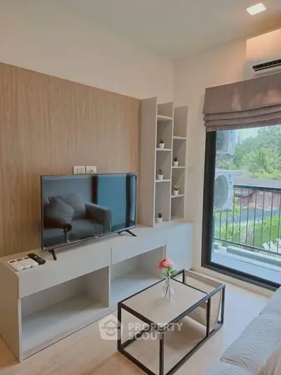 Modern living room with TV, stylish shelving, and balcony view