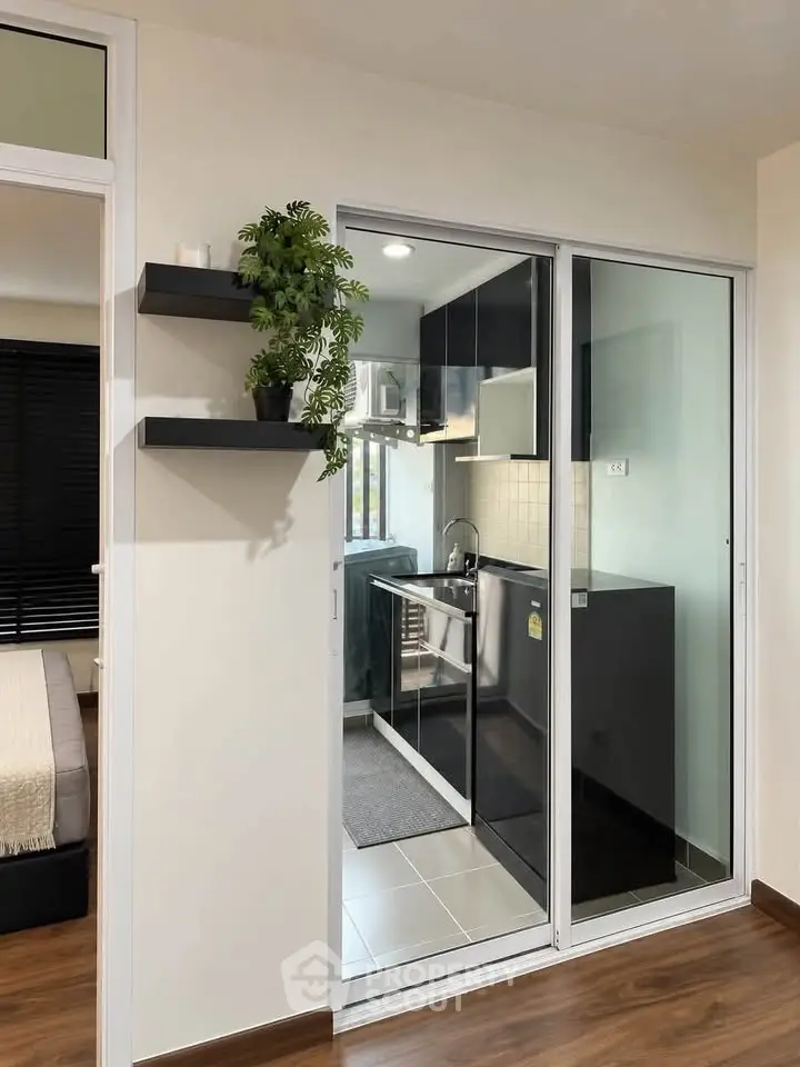 Modern apartment with sleek kitchen and cozy bedroom, featuring stylish decor and efficient use of space.