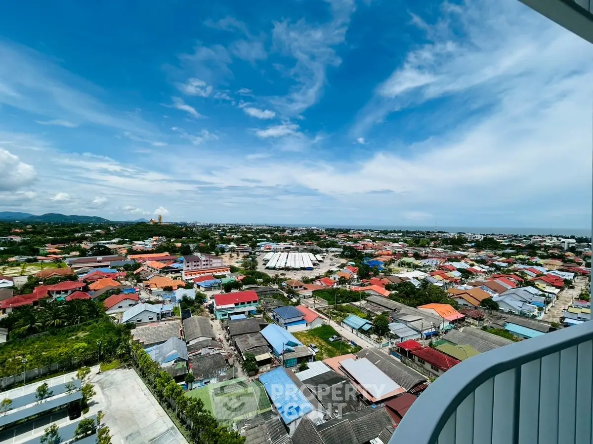Stunning panoramic view from high-rise balcony showcasing vibrant cityscape under clear blue sky.