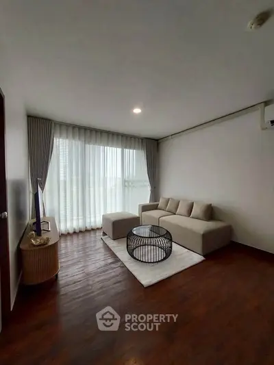 Modern living room with elegant sofa and large window, perfect for relaxation and natural light.
