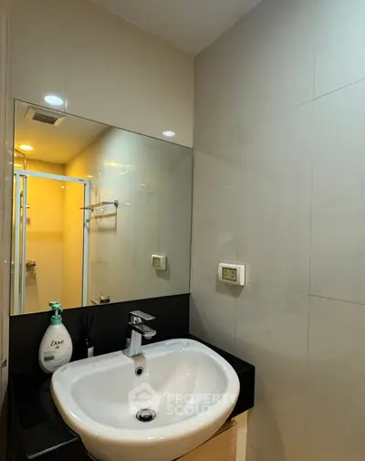 Modern bathroom with sleek sink and large mirror in contemporary apartment.