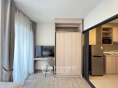Modern studio apartment with sleek design, featuring a cozy workspace and compact kitchen area.