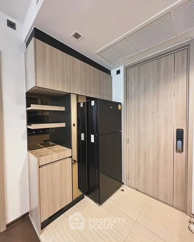 Modern kitchen with sleek black fridge and wooden cabinetry, showcasing contemporary design and efficient use of space.