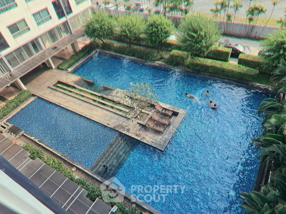 Luxurious residential pool area with sun loungers and lush greenery, perfect for relaxation and leisure.