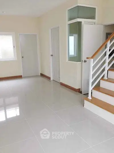 Spacious interior with modern staircase and sleek tiled flooring, perfect for contemporary living.