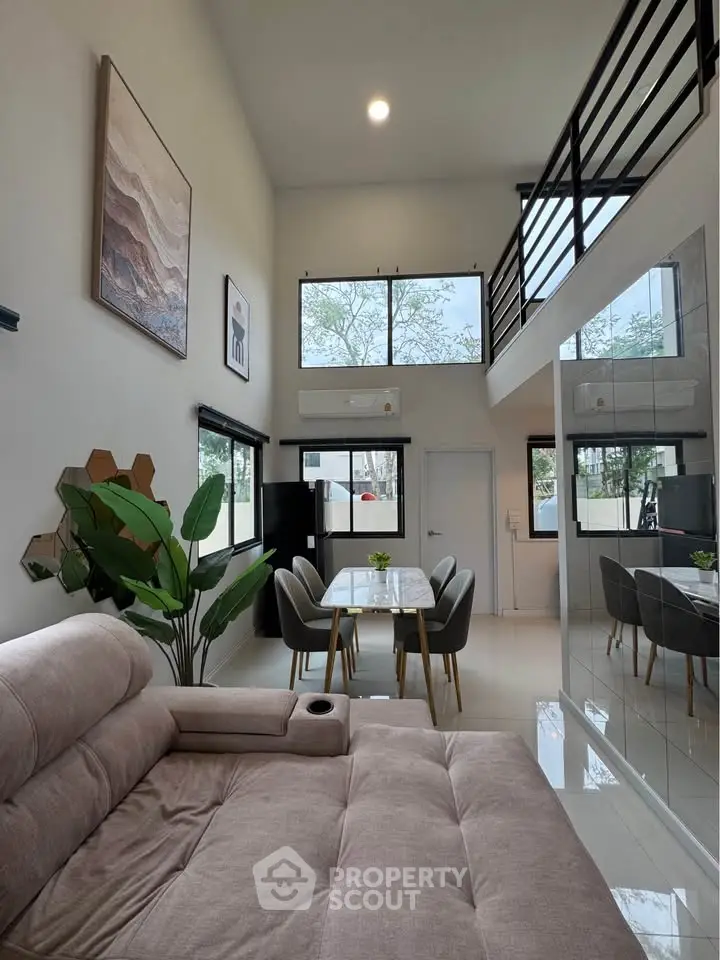 Modern living room with high ceiling, large windows, and stylish decor in a contemporary home.