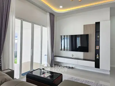 Modern living room with sleek TV setup and large sliding glass doors leading to patio.