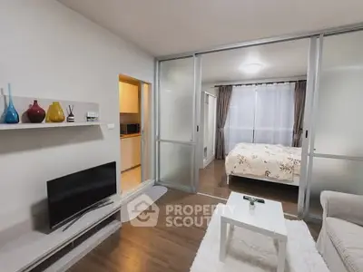 Modern studio apartment with cozy living area and bedroom separated by sliding glass doors.