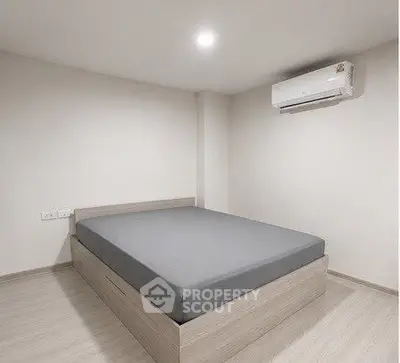 Minimalist bedroom with modern bed and air conditioning unit, perfect for a cozy living space.
