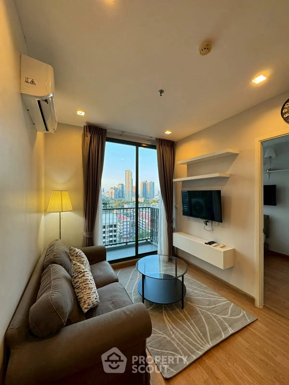 Modern living room with city view and balcony access in high-rise apartment.