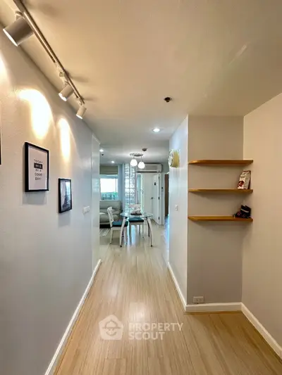 Modern hallway leading to a bright living area with stylish decor and wooden flooring.