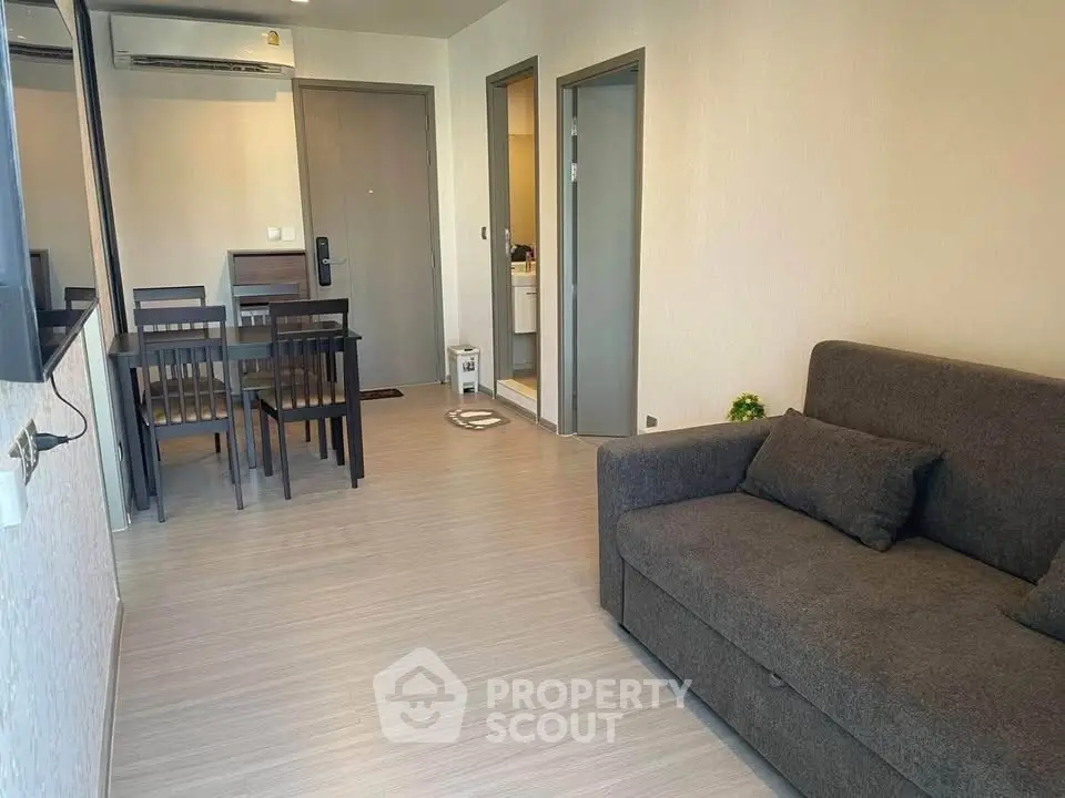 Modern living room with sleek furniture and dining area in open layout apartment.