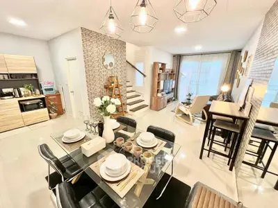 Modern open-plan living room with stylish kitchen and dining area, featuring contemporary lighting and decor.