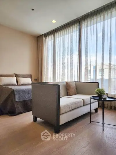 Modern bedroom with cozy seating area and large windows offering natural light.