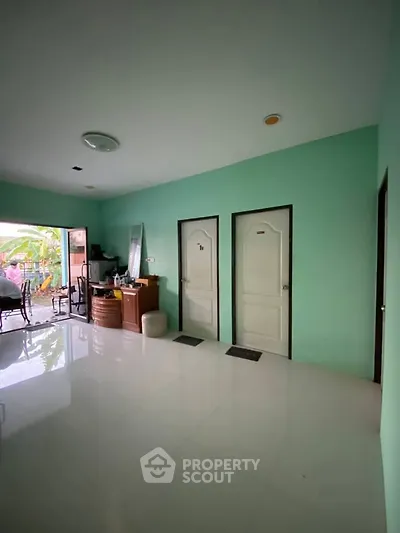 Spacious interior with glossy floors and vibrant green walls, featuring multiple doors and outdoor access.