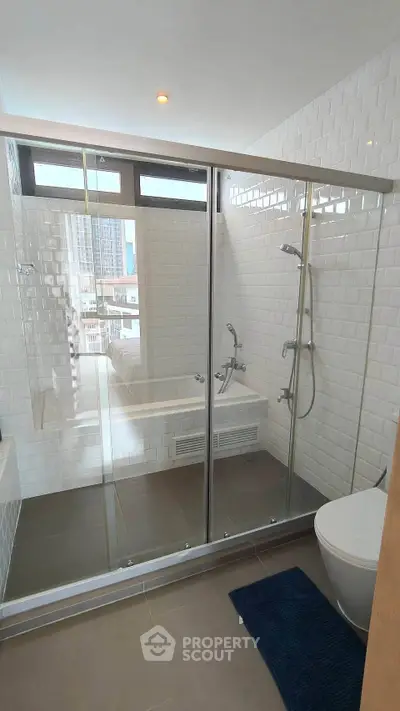 Modern bathroom with glass shower enclosure and city view window