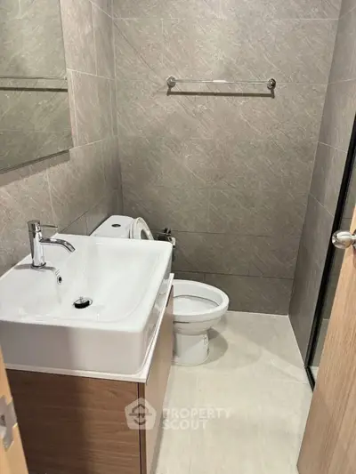 Modern bathroom with sleek fixtures and neutral tiles, featuring a compact design for efficient space use.