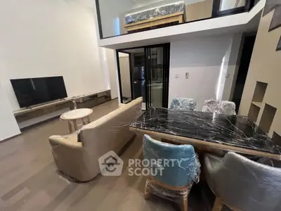 Modern living room with mezzanine, stylish furniture, and sleek TV setup.