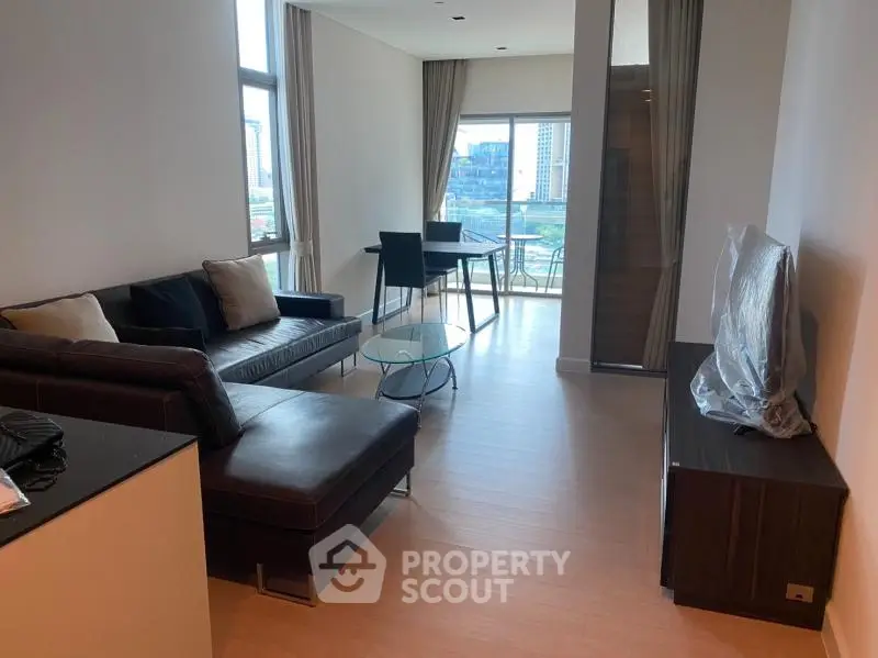 Modern living room with sleek furniture and city view balcony in high-rise apartment.
