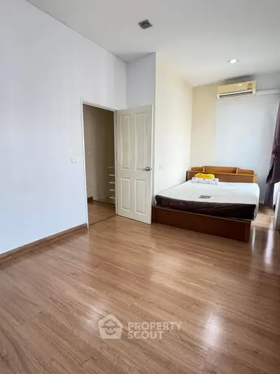 Spacious bedroom with wooden flooring and modern air conditioning unit.