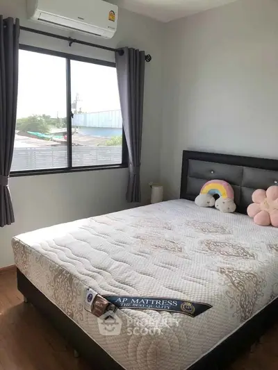 Cozy bedroom with large window and stylish decor, perfect for relaxation and comfort.