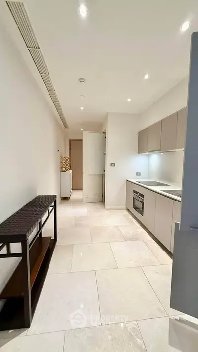 Modern kitchen with sleek cabinetry and built-in oven in a bright apartment.