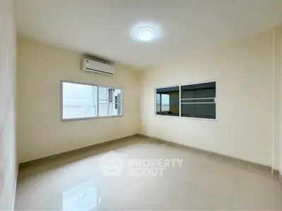 Spacious empty room with large windows and air conditioning, perfect for customization.