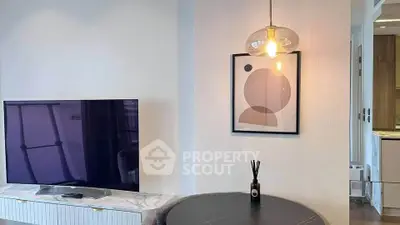 Modern living room with stylish decor and flat-screen TV, featuring elegant lighting and contemporary artwork.