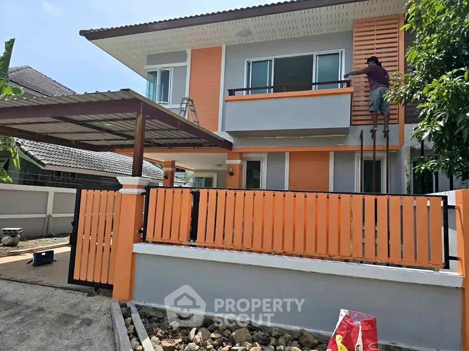 Modern two-story house with orange accents and a spacious driveway.
