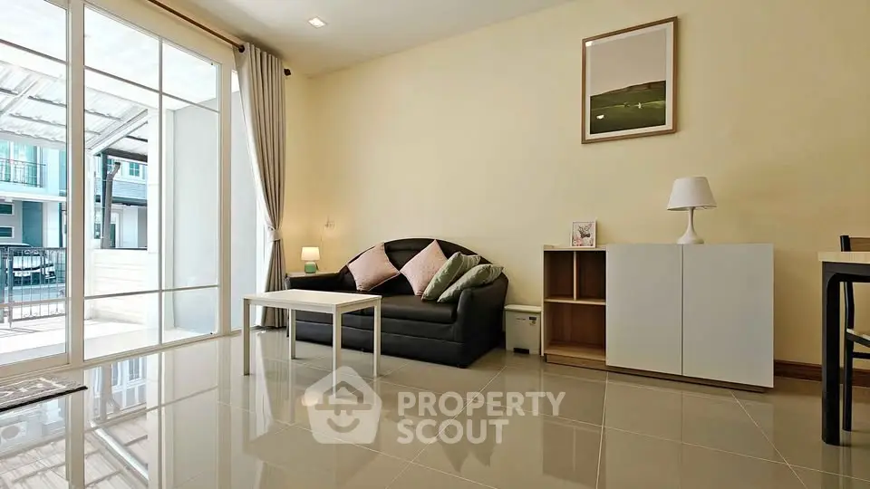 Modern living room with sleek furniture and large windows opening to a balcony.