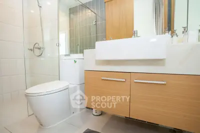 Modern bathroom with sleek fixtures and wooden cabinetry, featuring a glass-enclosed shower.
