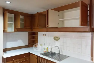 Spacious kitchen with wooden cabinets and white countertops, featuring an open layout and modern sink.