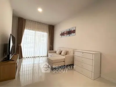 Modern living room with sleek white furniture and large window for natural light.