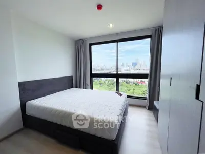 Modern bedroom with large window offering stunning city view and ample natural light.