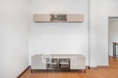 Modern minimalist living room with sleek storage unit and wooden flooring.