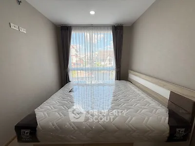 Cozy bedroom with large window and natural light, featuring a comfortable bed and modern decor.